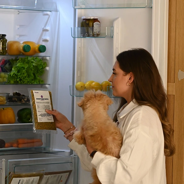 Kobieta wyjmuje z lodówki saszetke jedzenia