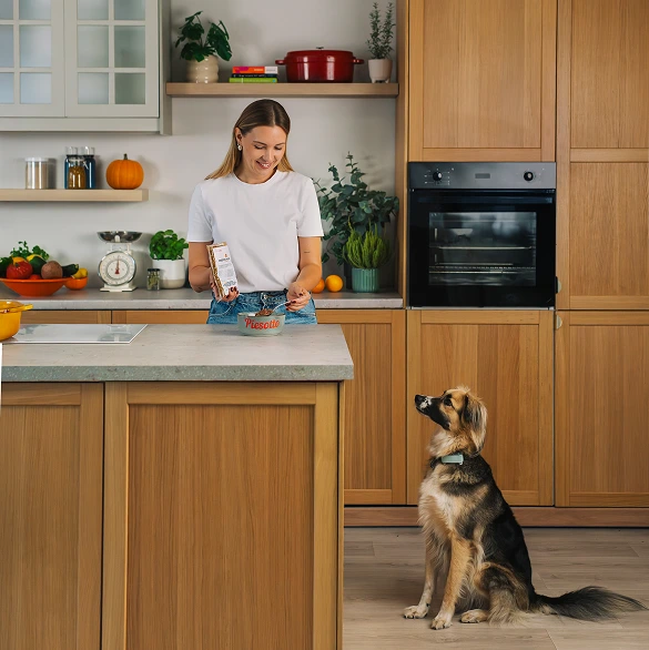 Dziewczyna karmi pieska w kuchni